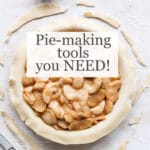 Apple pie being made with bottom crust in pan, topped with apple pie filling, scissors for trimming excess crust around edges and a little cup of flour for dusting if more pastry rolling is needed