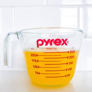 Warm clarified butter in a measuring cup is golden in colour and fluid
