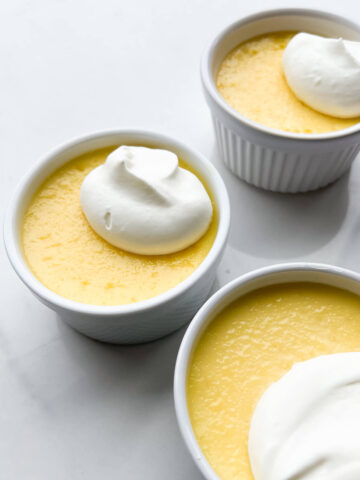 Ramekins of white chocolate custard topped with whipped cream.